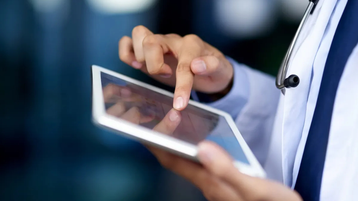 Close-up of medical professional interacting with data on a tablet.