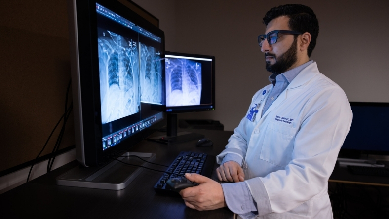 Doctor reviewing chest X-rays on medical monitors using clinical software